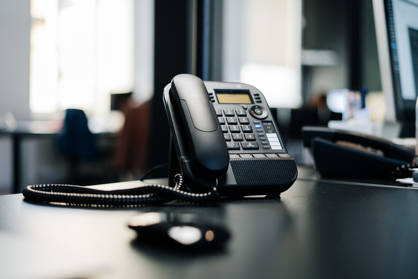 Schwarzes Tischtelefon auf einem Schreibtisch im Büro